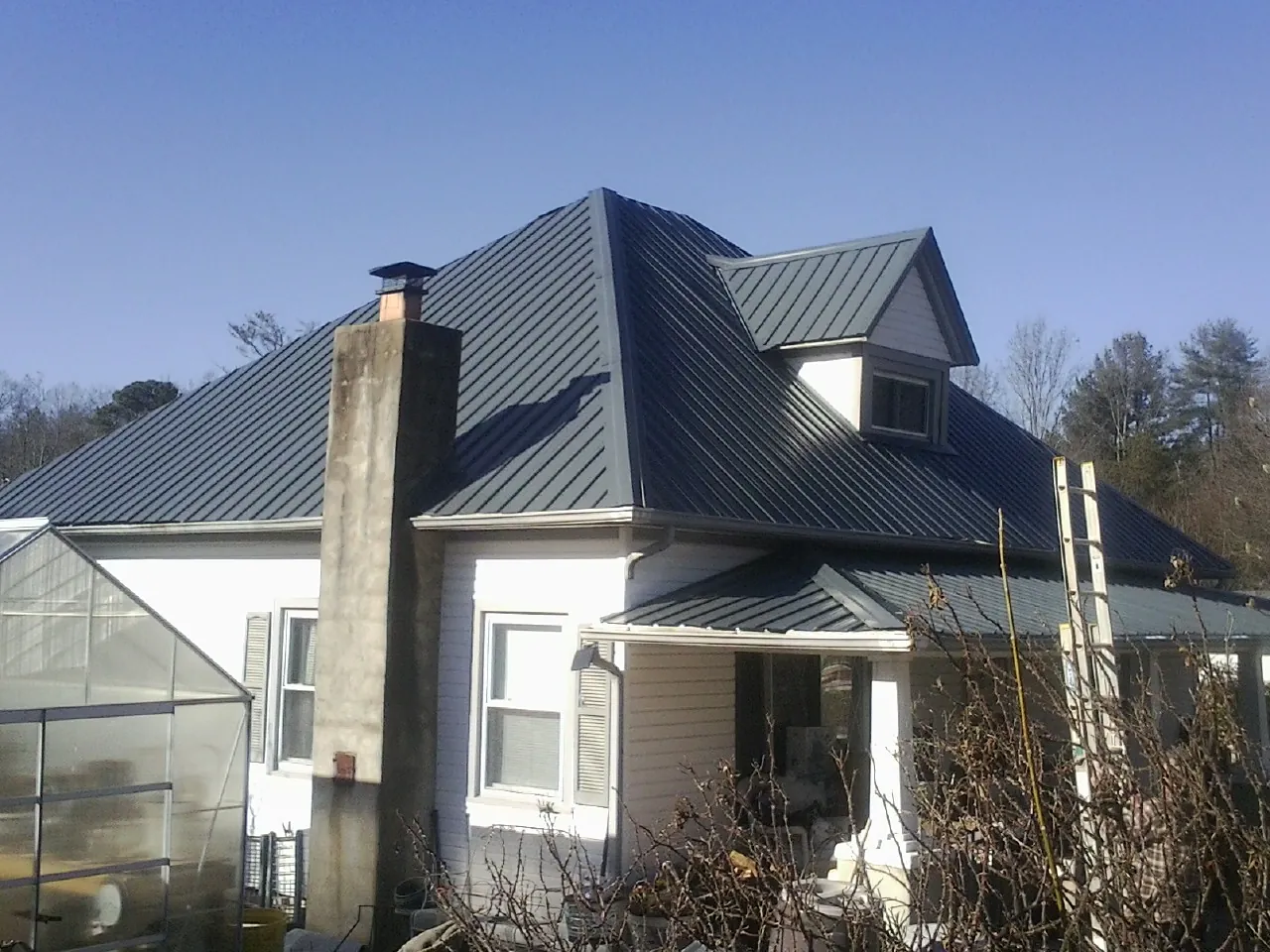 Dark blue standing seam metal roof on a white farmhouse with dormer — Slate & Tile Roof Repair by Roofing Brothers in Central Bridge