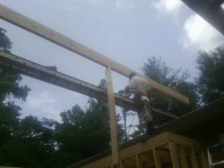Carpenter setting a ridge beam over a new addition frame — Ice Dam Removal by Roofing Brothers in Central Bridge
