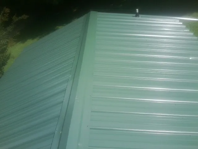 New green metal panels meeting at the ridge of a roof — Flat Roof Repair work by our crew in Central Bridge