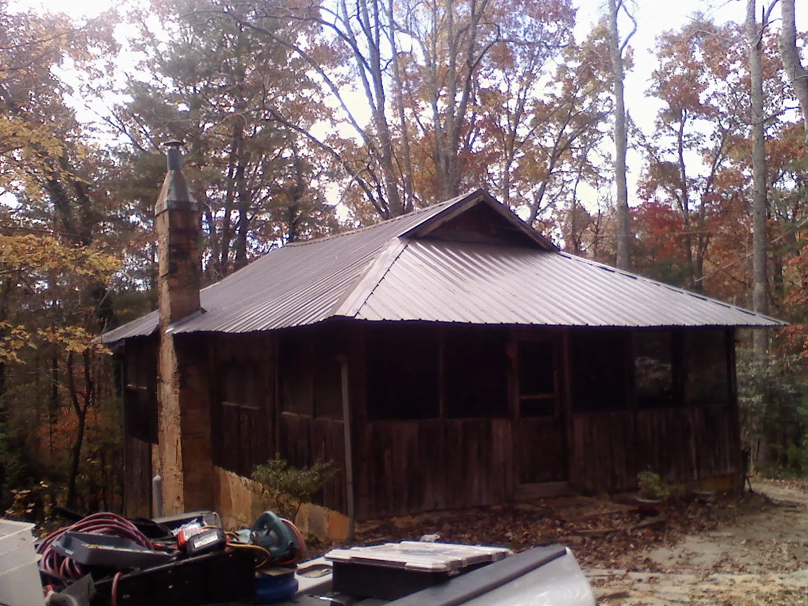 Brown metal hip roof on an old cabin with a stone chimney in Central Bridge