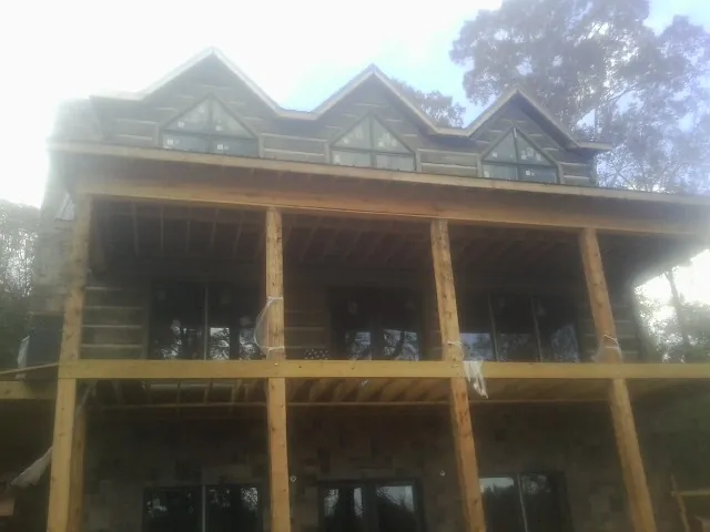 Dormers and porch framing on a large log home under construction — Roof Coating work by our crew in Central Bridge