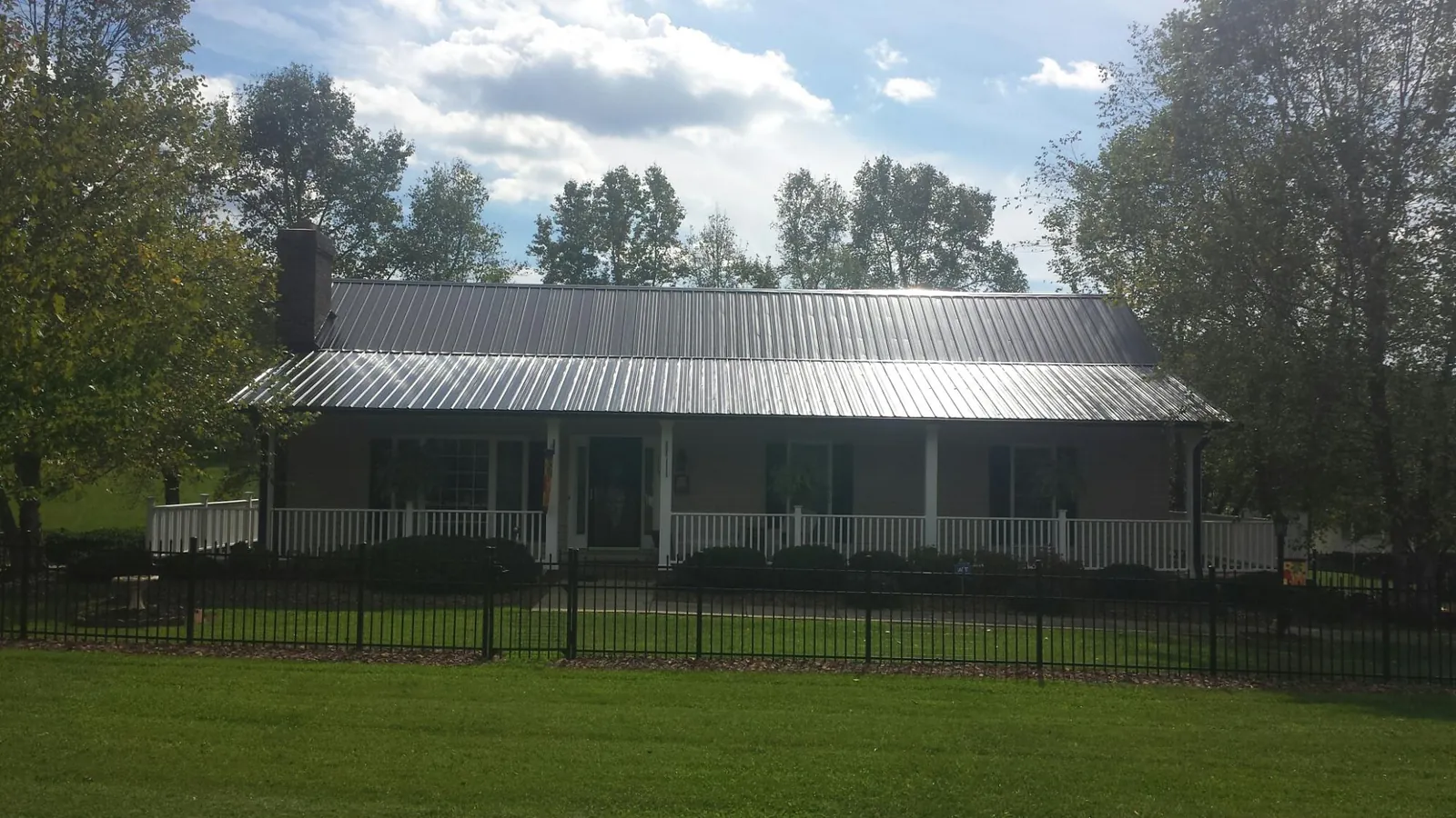 Gray metal roof on a brick ranch with a full width front porch — Gutter Guard Installation work by our crew in Central Bridge