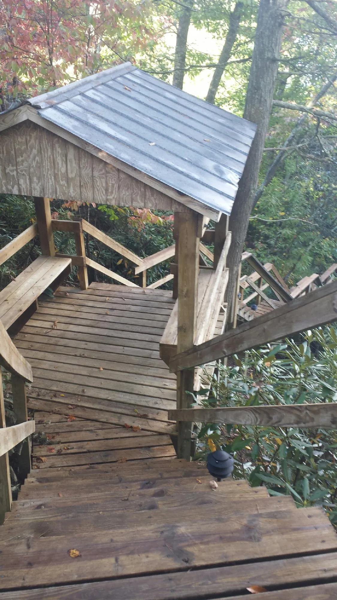 Metal roofed shelter over wooden steps on a wooded walkway — Skylight Repair & Installation work by our crew in Central Bridge