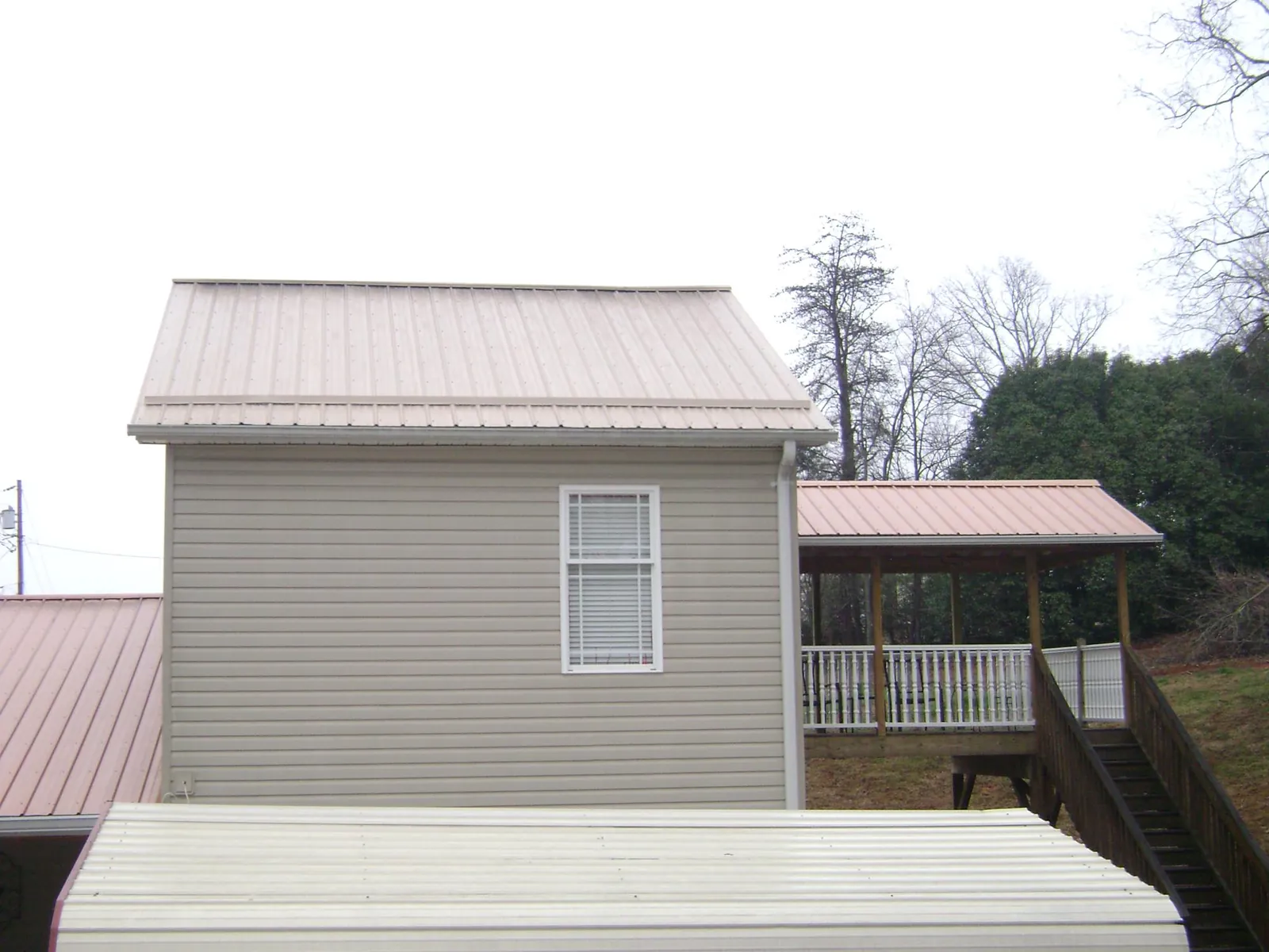 Tan metal roofs on a two story addition and attached porch, from a Roof Replacement job in Central Bridge