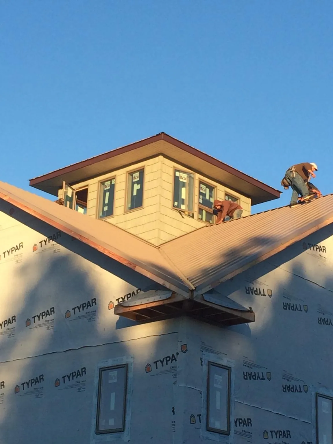 Roofers working around a rooftop cupola on a new metal roof at sunset — Roof Waterproofing in Central Bridge by Roofing Brothers